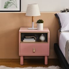 a pink nightstand next to a bed in a bedroom