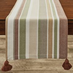 a striped table runner with tassels on the edge and two wooden chairs in the background