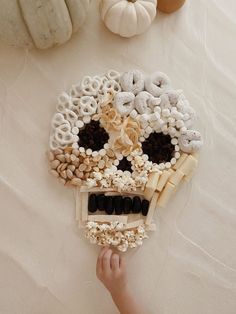 a skull made out of cereals and other items sitting on a table next to pumpkins