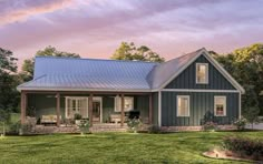 a blue house with a metal roof in the middle of a grassy field at sunset