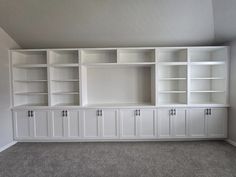 an empty living room with white cabinets and carpeted flooring in the middle of it