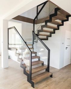 a stair case in the middle of a room with wooden floors and white walls,