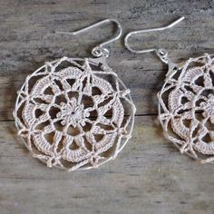 crocheted earrings with silver hooks on wooden background, closeup photo taken from above