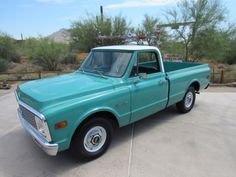 a turquoise pick up truck parked in a parking lot