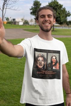 a man in a white t - shirt is holding his hand up to the camera