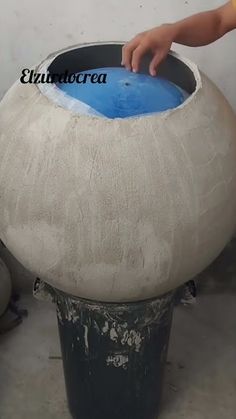 a person is touching the bottom of a large pot that has been made out of cement