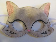 a gray cat mask with black eyes and pink ears on a white table cloth background