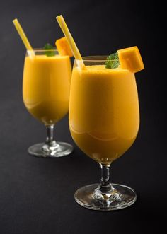 two glasses filled with orange juice and garnished with mint