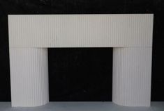 a large white fireplace with two columns on each side and a black wall behind it