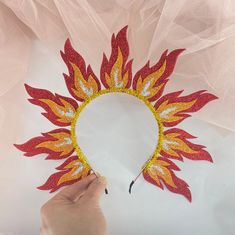 someone is making a firework headband out of red and yellow glittered paper