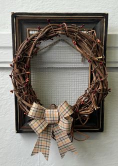 a wreath is hanging on the wall next to a frame with a bow tied around it