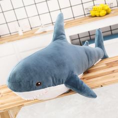 a stuffed shark laying on top of a wooden table