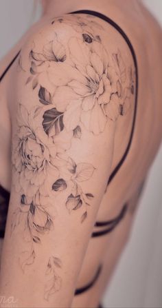 a woman's arm with flowers and leaves tattooed on the back of her shoulder