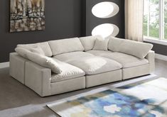 a large white sectional couch in a living room with grey walls and rugs on the floor