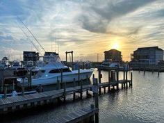 the sun is setting over some boats docked