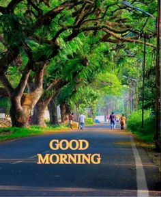 people walking down the road with trees on either side and good morning written in yellow