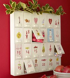 a white calendar with red numbers and green leaves on it sitting next to two apples