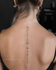 the back of a woman's neck with an arrow and flowers tattoo on it