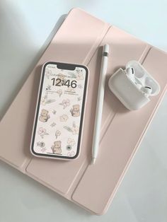 an iphone and ear buds are sitting on a pink tabletop next to a pen