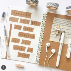 an open book with earbuds on top of it next to some other items