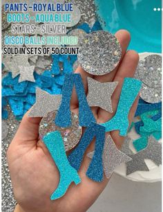 a hand holding several pieces of blue and silver glittered paper with stars on them