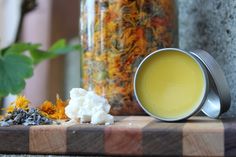 a glass jar filled with yellow liquid sitting on top of a table next to flowers