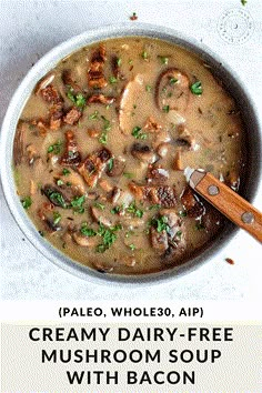 a bowl filled with mushroom soup on top of a white counter next to a wooden spoon