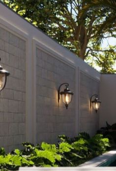 three lights are on the side of a wall next to a swimming pool and trees