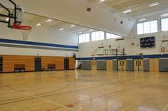 an indoor basketball court with yellow and blue lines on the floor, surrounded by large windows