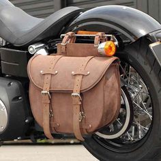 a close up of a motorcycle with a leather bag on it's front tire