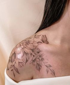 a close up of a woman's shoulder with flowers and butterflies on the chest