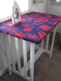 an ironing board on top of a table with a blue and red flowered cover