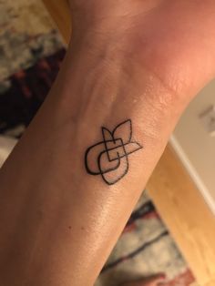 a small tattoo on the wrist of a woman's arm, with an intertwined design