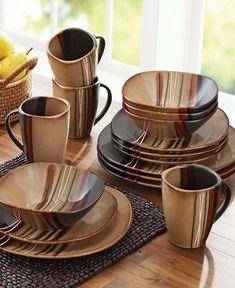 a set of black and gold dinnerware on a wooden table with bananas in the background