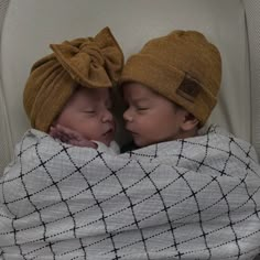 two babies wrapped up in blankets and hats, one is sleeping while the other sleeps