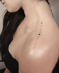 the back of a woman's shoulder with an arrow and stars tattoo on it