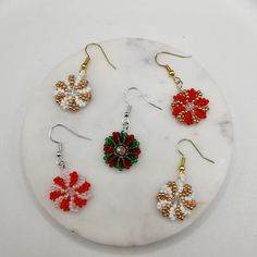 Product Description: This set of earrings is handcrafted with 2mm  seed beads and 4mm faceted beads, featuring unique snowflake and swirl patterns. The classic red, green, gold, and white color scheme combined with the sparkle of faceted beads perfectly captures the festive spirit of Christmas. These earrings add a touch of elegance and charm to your holiday outfits. Material: High-quality 2mm seed beads, 4mm faceted beads, with gold-plated/silver-plated hooks Design: Snowflake and swirl pattern Knit With Beads, Gold And White Color Scheme, Bead Shapes, Holiday Beading, Earrings Patterns, Beaded Jewlery, Snowflake Earrings, White Color Scheme, Beading Crafts