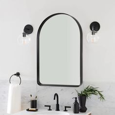 a bathroom sink with an oval mirror above it and black faucets on the wall