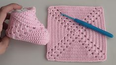 someone is crocheting a baby boot on top of a blanket with a blue pen