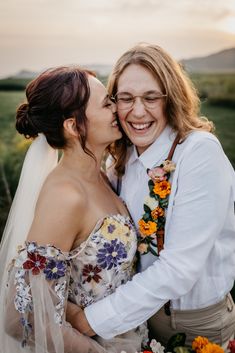 two women are hugging each other in front of the camera and flowers around their necks