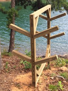 a wooden structure sitting on top of a dirt field next to a body of water