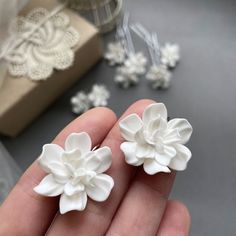 two white flowers are being held in someone's hand next to some other items