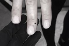 a woman's hand with white nails and a black diamond ring on her finger