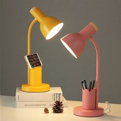 a pink and yellow desk lamp sitting on top of a table next to a stack of books