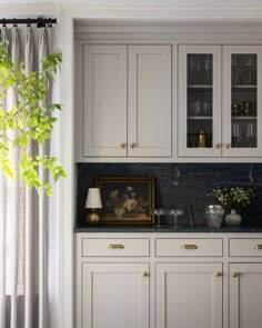 a kitchen with white cabinets and black marble counter tops, along with a potted plant