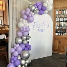 the balloon arch is decorated with purple and silver balloons for an 90th birthday party