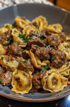 a plate full of pasta with meat and sauce on it, sitting on a table