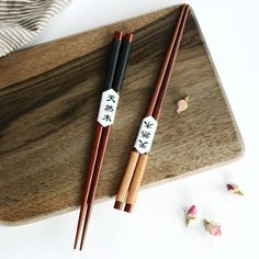 two chopsticks sitting next to each other on a cutting board with dried flowers