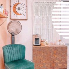 a green chair sitting in front of a window next to a dresser and coffee maker