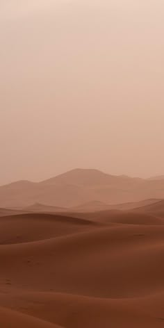 two people riding horses in the desert with sand dunes behind them and mountains in the distance